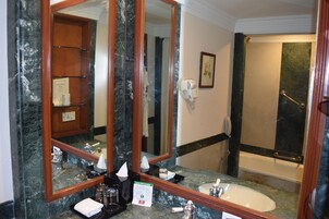 A bathroom with a marble sink, a large mirror, a towel rack, a hairdryer, and a shower area.