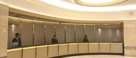 A hotel reception area with a curved counter, a modern ceiling design, and a clean, polished floor.