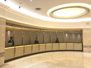 Guests can check in at the reception area, featuring a curved counter and service booths.