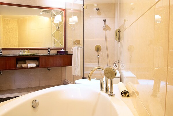 A modern bathroom with a large white bathtub, a glass-enclosed shower, and a vanity with a mirror and towel rack. - Grandview Hotel Macau (Taipa)