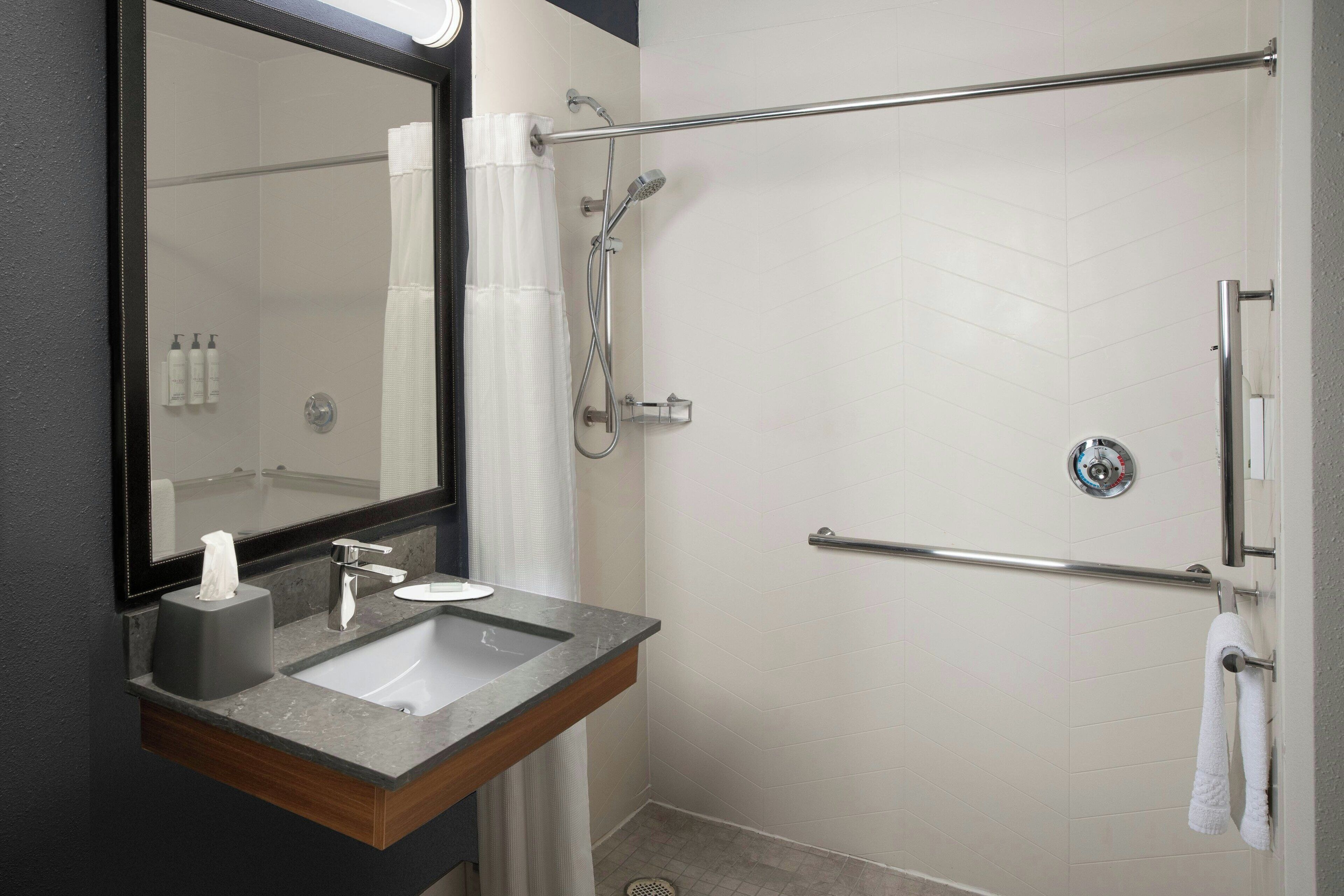 A modern bathroom with a sink, mirror, and shower.