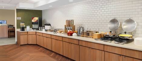 Una cocina moderna con una encimera larga, diversos alimentos y un reloj en la pared.