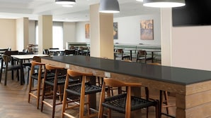 Un comedor moderno con una barra alargada, sillas de madera e iluminación colgante.