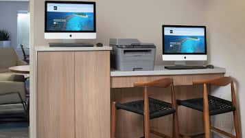 A desk with two monitors, a keyboard, a printer, and two chairs.