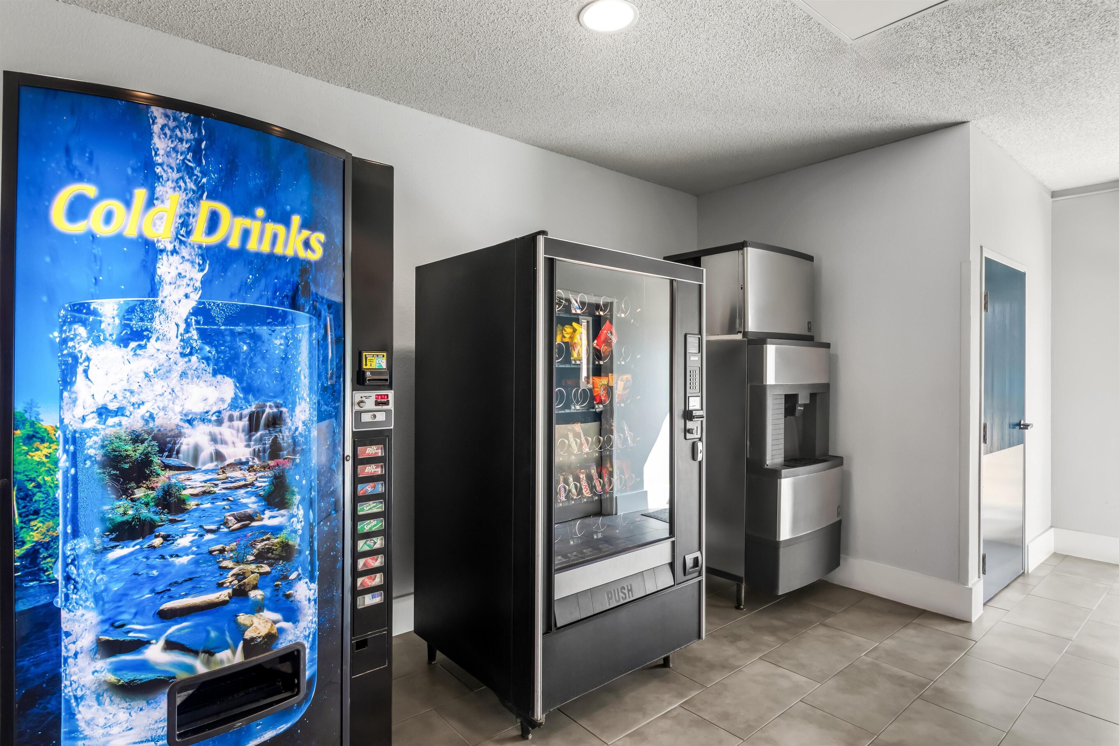A hotel lobby with a cold drink vending machine, a refrigerator, and a microwave.