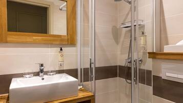 A bathroom with a white sink, a mirror, and a glass-enclosed shower.