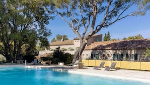 Una piscina nítida amb gandules i un edifici amb teulada d'estuc al fons.