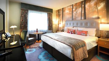 Una habitación de hotel con cama, mesitas de noche, escritorio con teléfono, una silla y ventana con cortinas.
