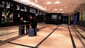 Een hotel receptie met een balie, een scherm dat informatie toont en een glazen scheidingswand.