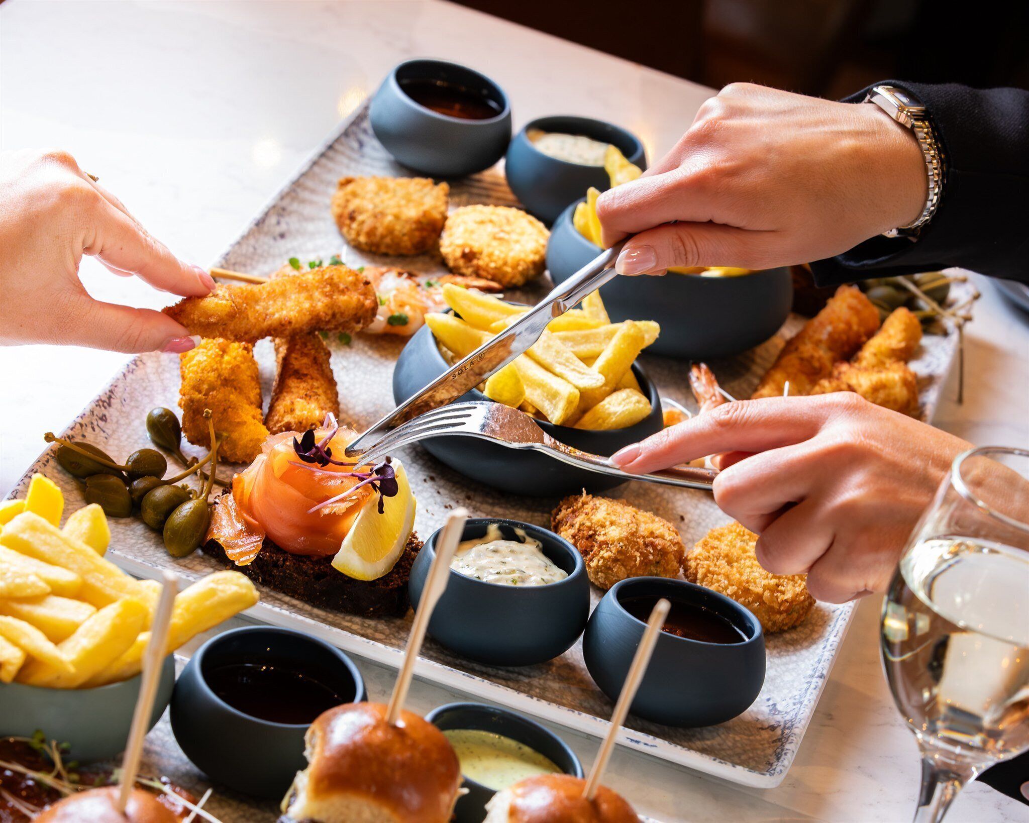 A dining table with various seafood dishes, including breaded fish and fries, and small bowls of dipping sauces.
