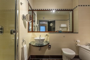 A bathroom with a glass sink, a toilet, and a shower.