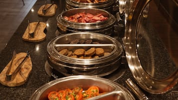 Buffet amb diferents aliments, com ara salsitxes, bacon i pollastre a la planxa.