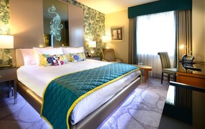 A hotel room with a large bed, a desk with a telephone, and a chair.
