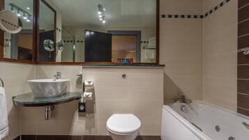 A modern bathroom with a glass sink, a white toilet, and a bathtub.