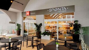 Un restaurante moderno llamado 'SPONTA PIZZA BAR' con terraza y plantas en macetas.