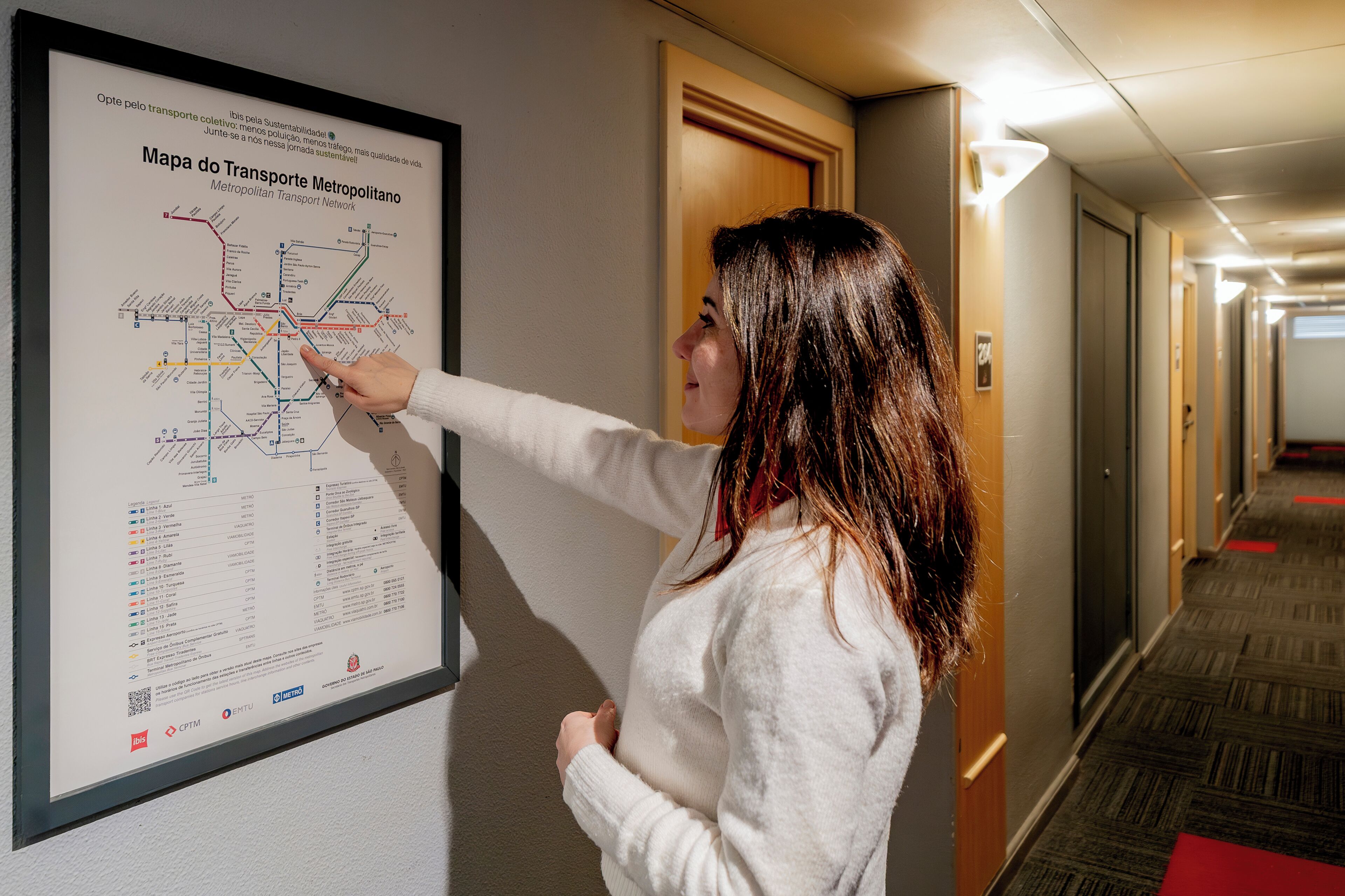 Une personne qui montre une carte accrochée au mur dans un couloir.