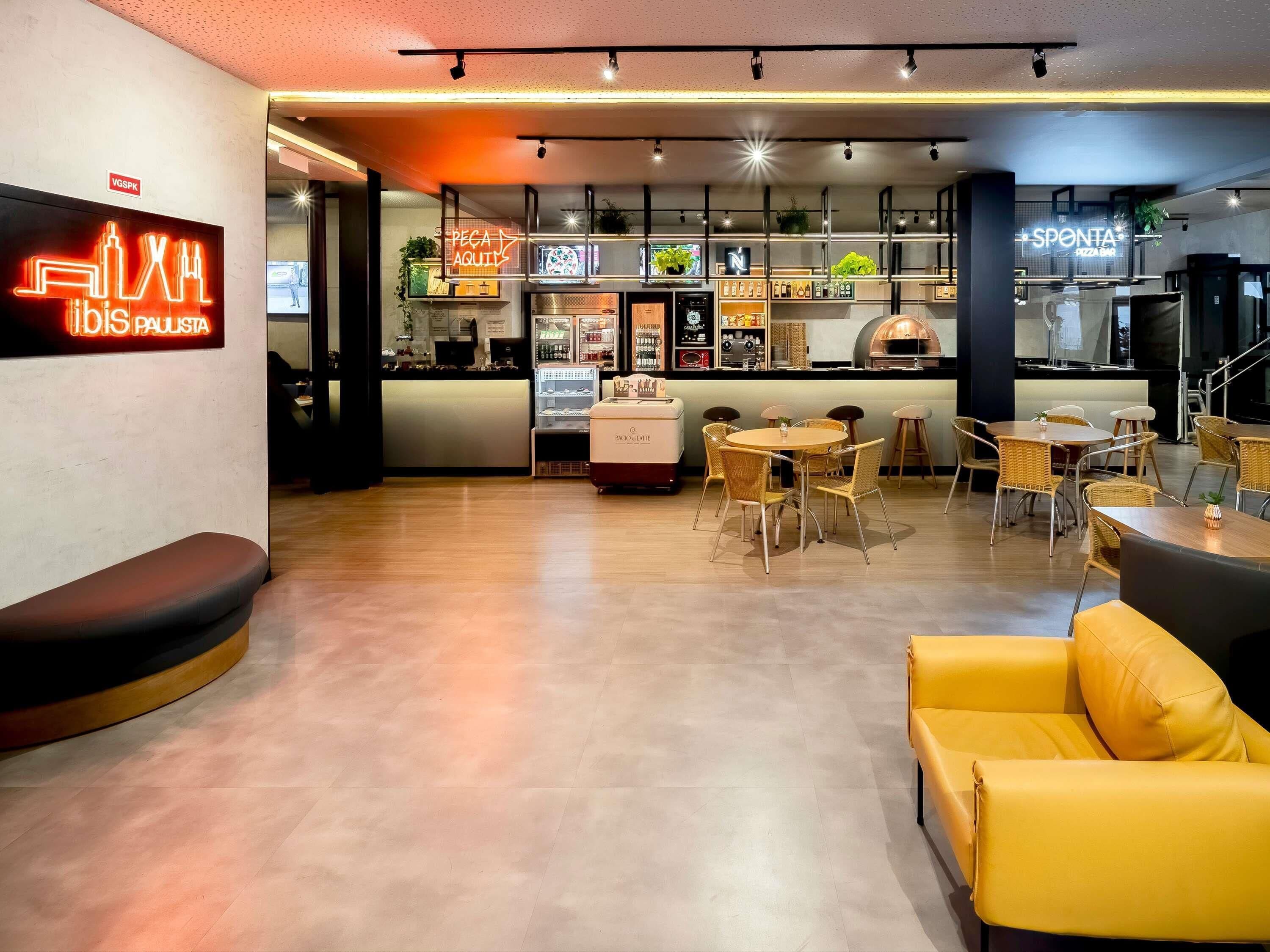 Un interior moderno con una zona de bar, asientos y una cocina visible al fondo.