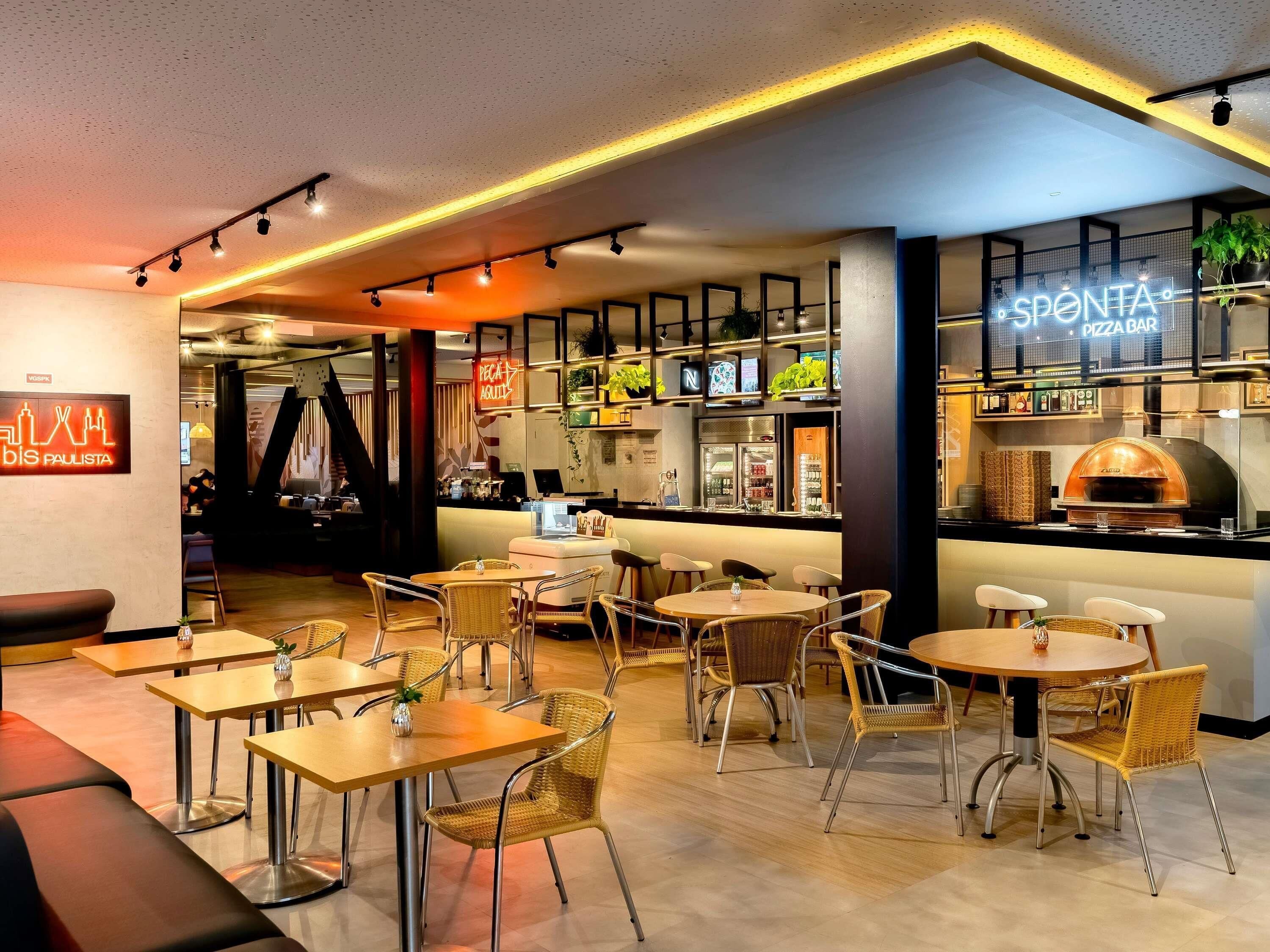 A modern restaurant interior with a bar area, seating arrangements, and a pizza oven.