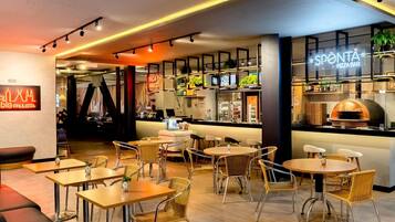 A modern restaurant interior with a bar area, seating arrangements, and a pizza oven.