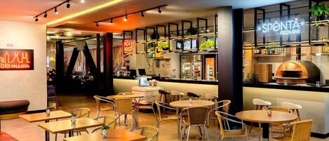 A modern restaurant interior with a bar area, seating arrangements, and a pizza oven.