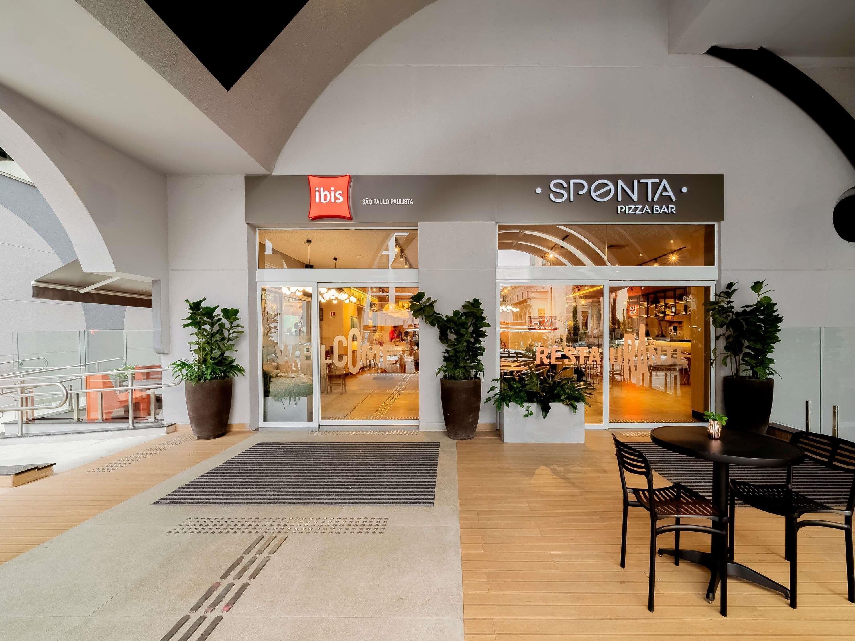 A modern interior with a restaurant named 'SPONTA PIZZA BAR' and a store named 'ibis São Paulo Paulista'.