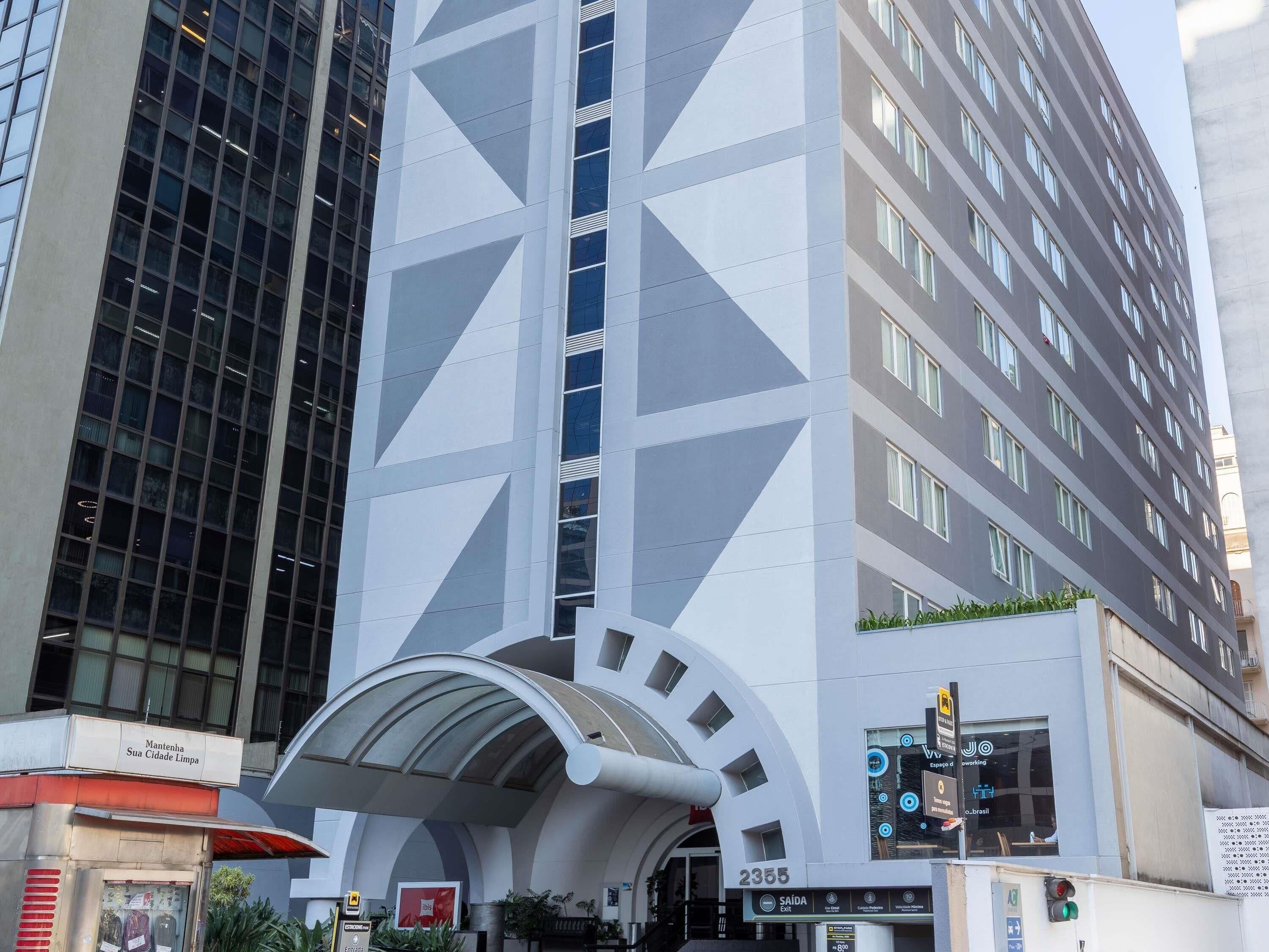 A modern building with a geometric facade, a covered entrance, and a sign indicating a specific exit.