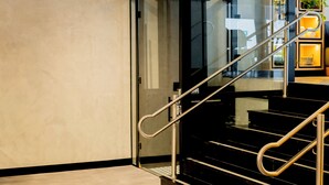 Una escalera moderna con barandillas de vidrio y pasamanos metálicos.