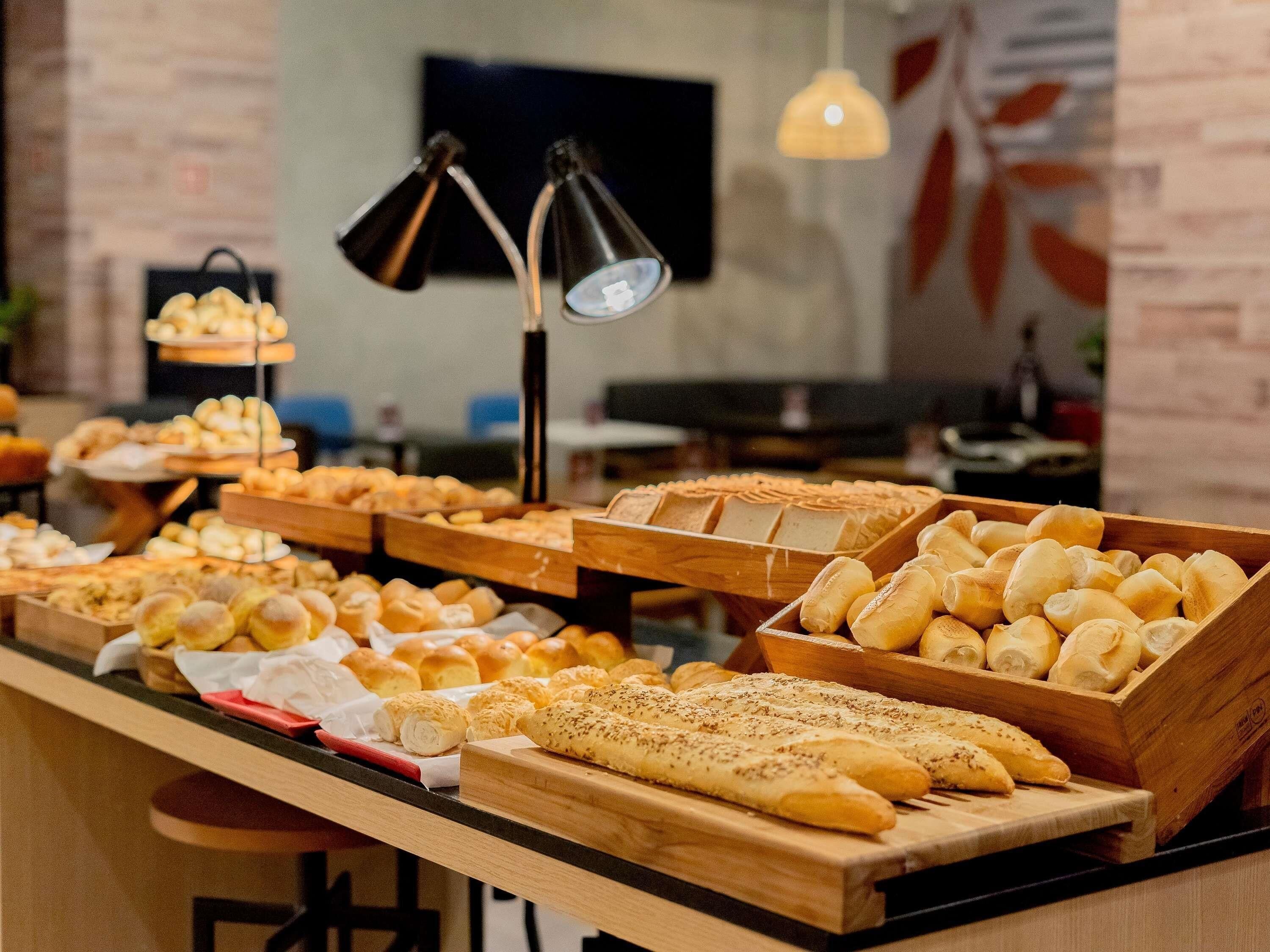 A buffet with various baked goods and a modern interior with brick walls and pendant lighting.
