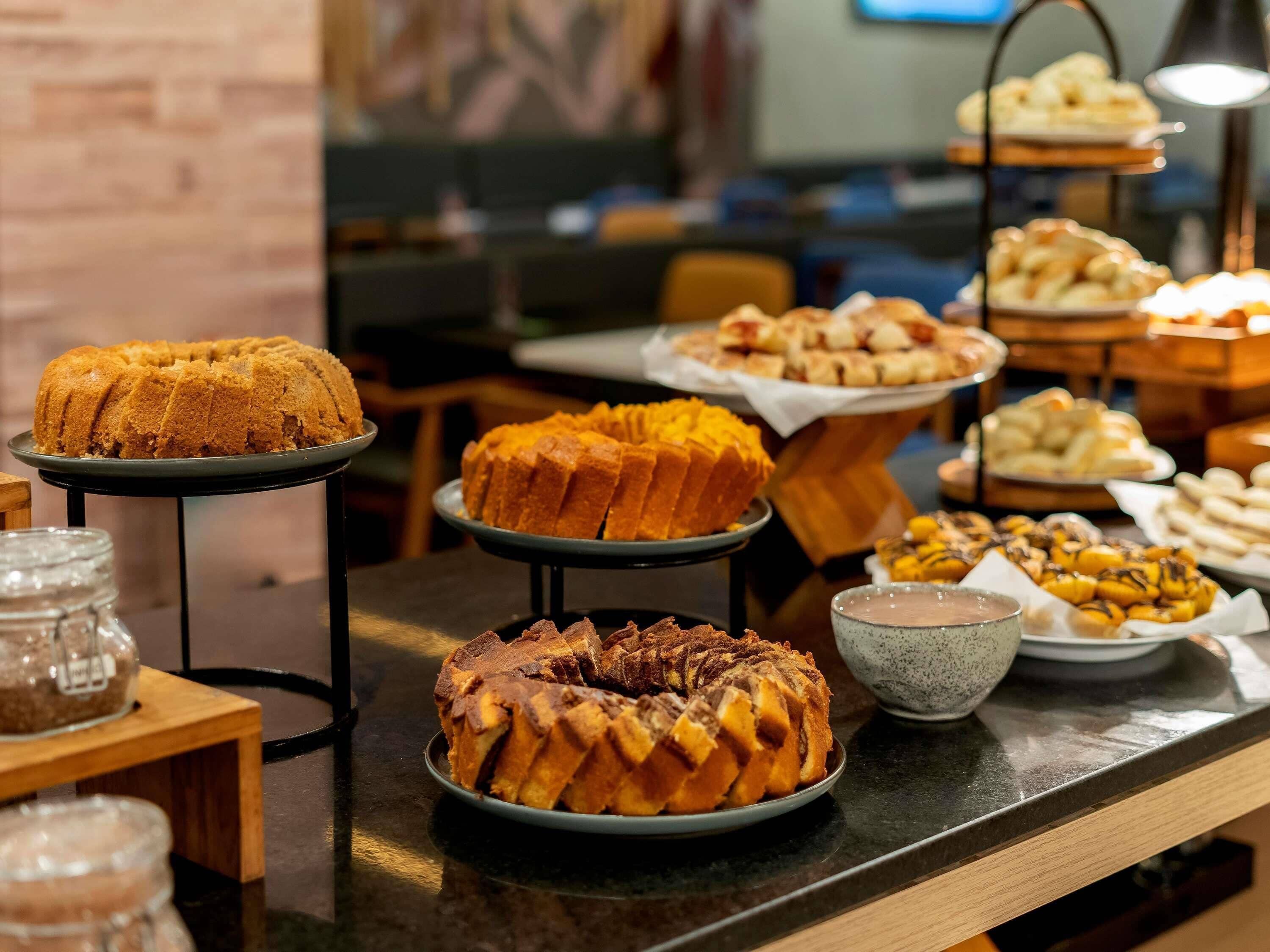 Buffet com diversos produtos de panificação e um bolo exposto.