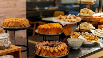 Buffet com diversos produtos de panificação e um bolo exposto.