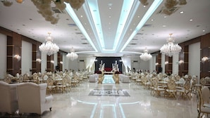 Un'ampia sala da banchetti con lampadari, tavoli e sedie disposti per un evento formale.