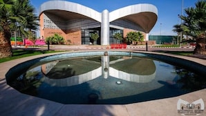 Un edificio moderno con un tetto curvo originale e una fontana centrale.