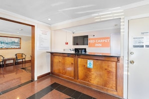 A reception desk with a sign for Red Carpet Inn, a framed picture on the wall, and a door with a sign indicating it's for employees only. - PHL Airport Inn - Philadelphia Airport (Essington)