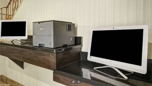 Et værelse med et mørkt træskrivebord, to skærme og en printer.