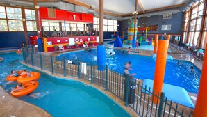 An indoor swimming pool with multiple lanes, a children's play area, and a seating area with a red and yellow color scheme. - Bridge Vista Beach - Hotel & Convention Center (Mackinaw City)