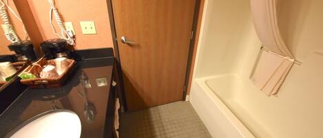 A bathroom with a sink, a mirror, a hairdryer, and a towel rack.