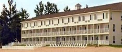 A multi-story hotel with balconies, located near a body of water.