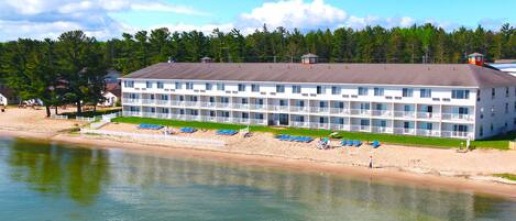 A multi-story hotel with a beachside location, featuring balconies and a pool area.