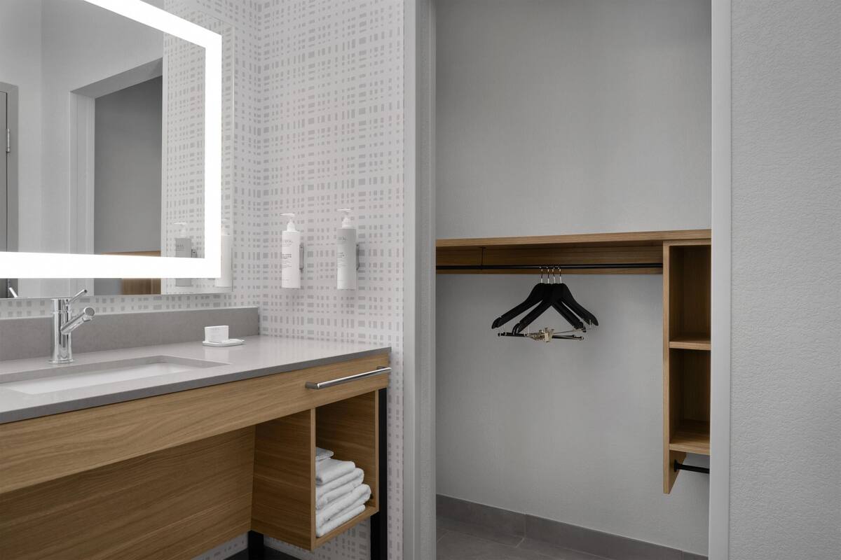 A modern bathroom with a large mirror, a sink, and a wooden vanity.