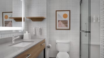 Een moderne badkamer met een grote spiegel, een houten wastafelmeubel, een toilet en een douchehoek.