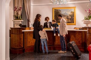 A reception desk with a sign reading "RECEPTION," a chandelier, and a painting on the wall.