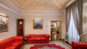Una stanza con un divano in pelle rossa, una grande orologio e un quadro appeso al muro.
