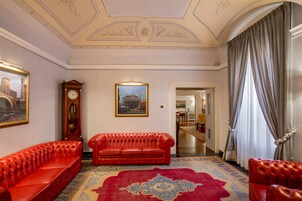 A room with a red leather sofa, a large clock, and a framed picture on the wall.