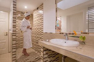 A modern bathroom with a patterned tile backsplash, a large mirror, and a white sink.