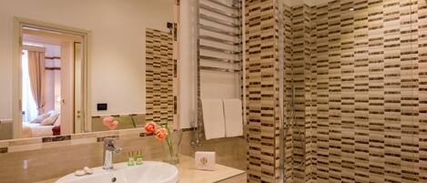A modern bathroom with a large mirror, a sink, a bidet, and a shower area with patterned tiles.