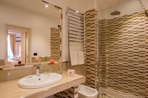 A modern bathroom with a large mirror, a sink, a bidet, and a shower area with patterned tiles.