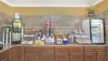 Una kitchenette equipada con cafetera, refrigerador, tostadora y dispensador de café.