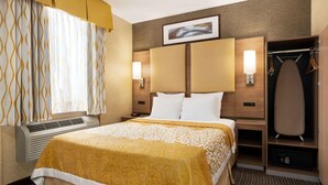 Una habitación de hotel con cama, armario, espejo y una lámpara fijada a la pared.