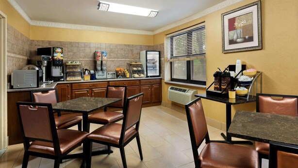 Cocina de hotel compacta con zona de comedor, equipada con cafetera, refrigerador, microondas y un refrigerador pequeño.