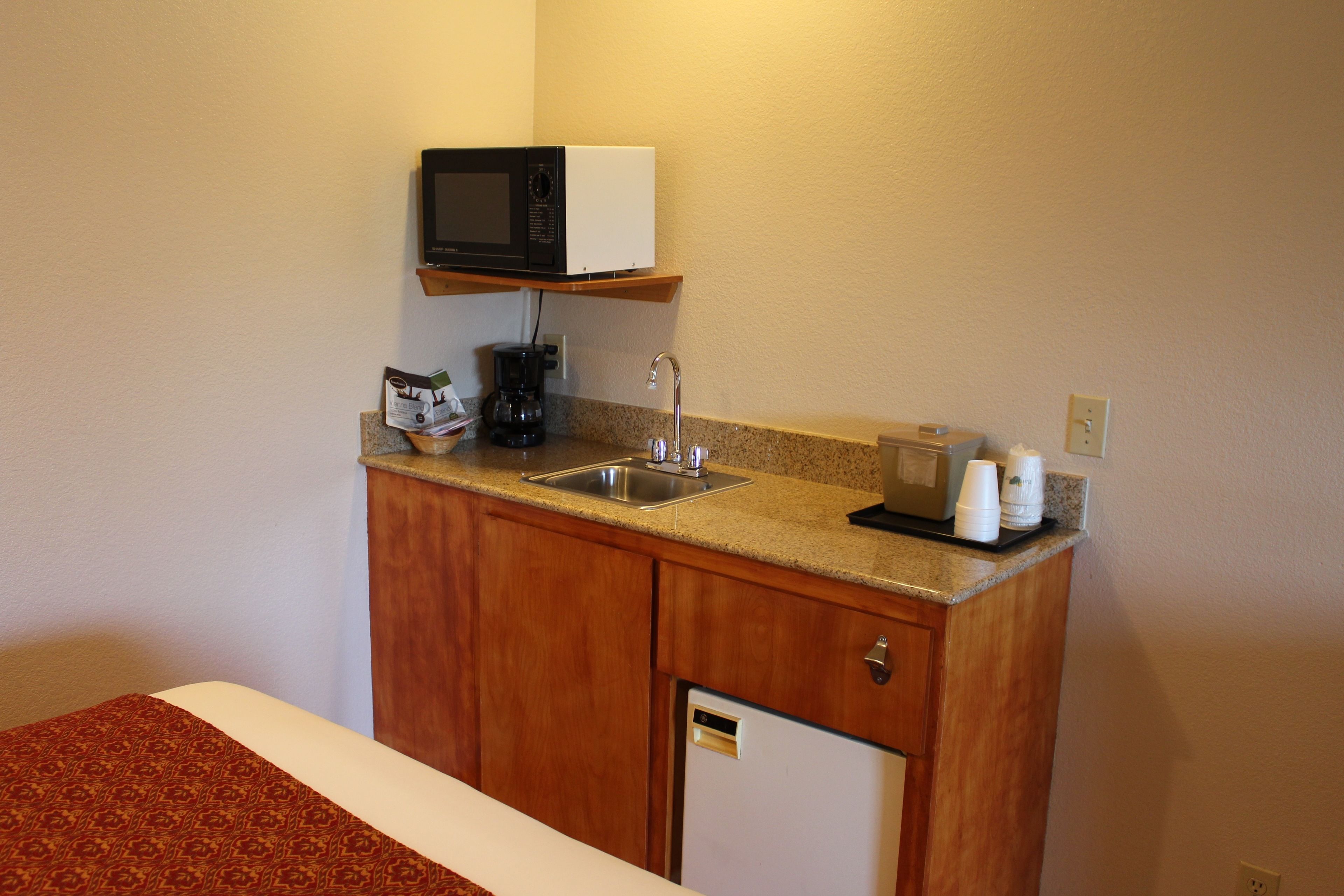 A compact kitchenette with a microwave, coffee maker, and a small refrigerator.